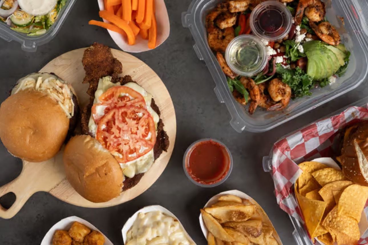 Overhead spread of burgers, wings, fries, and salads at The Porch